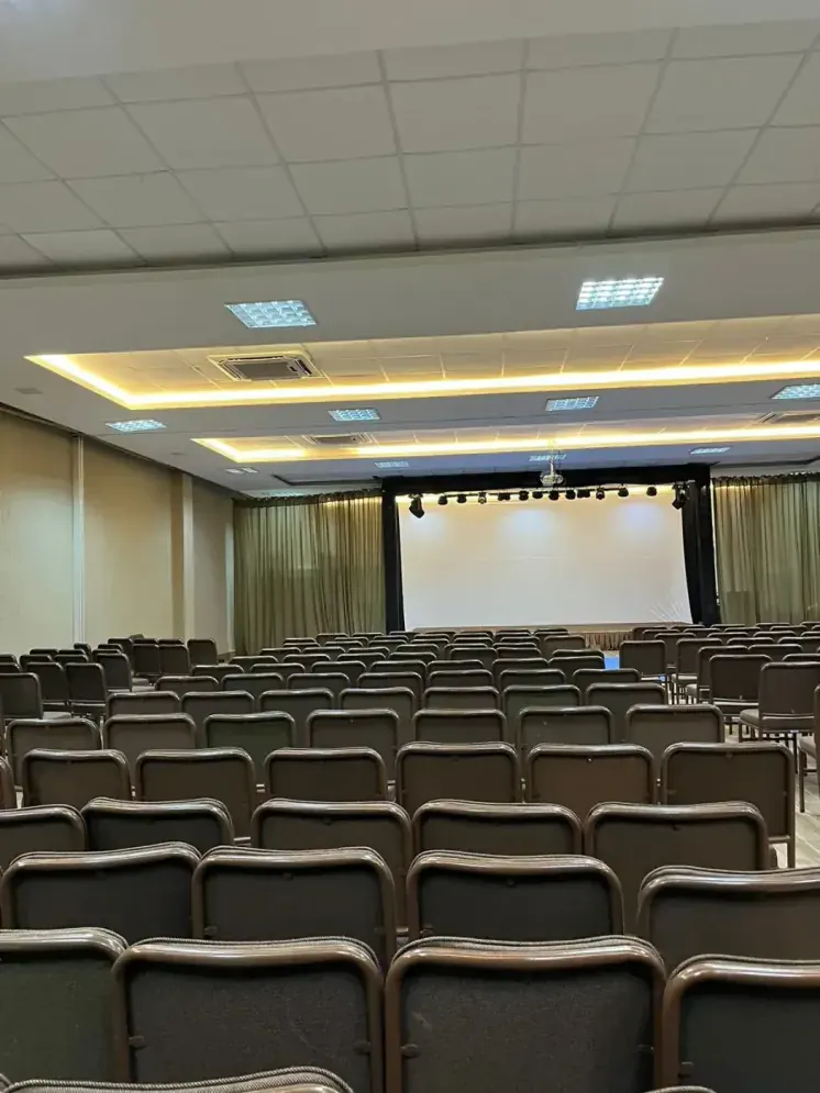 Salão do Samoa Beach Resort montado em auditório, com palco, telão e cadeiras enfileiradas