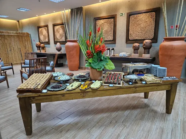 Mesa de coffee break servida no foyer de recepção, com decoração regional