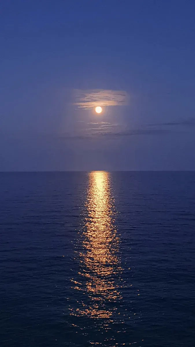 Lua quase cheia baixa no horizonte, sobre o mar de Muro Alto