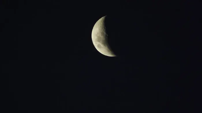 Lua crescente no céu escuro sobre a praia de Muro Alto, em Ipojuca