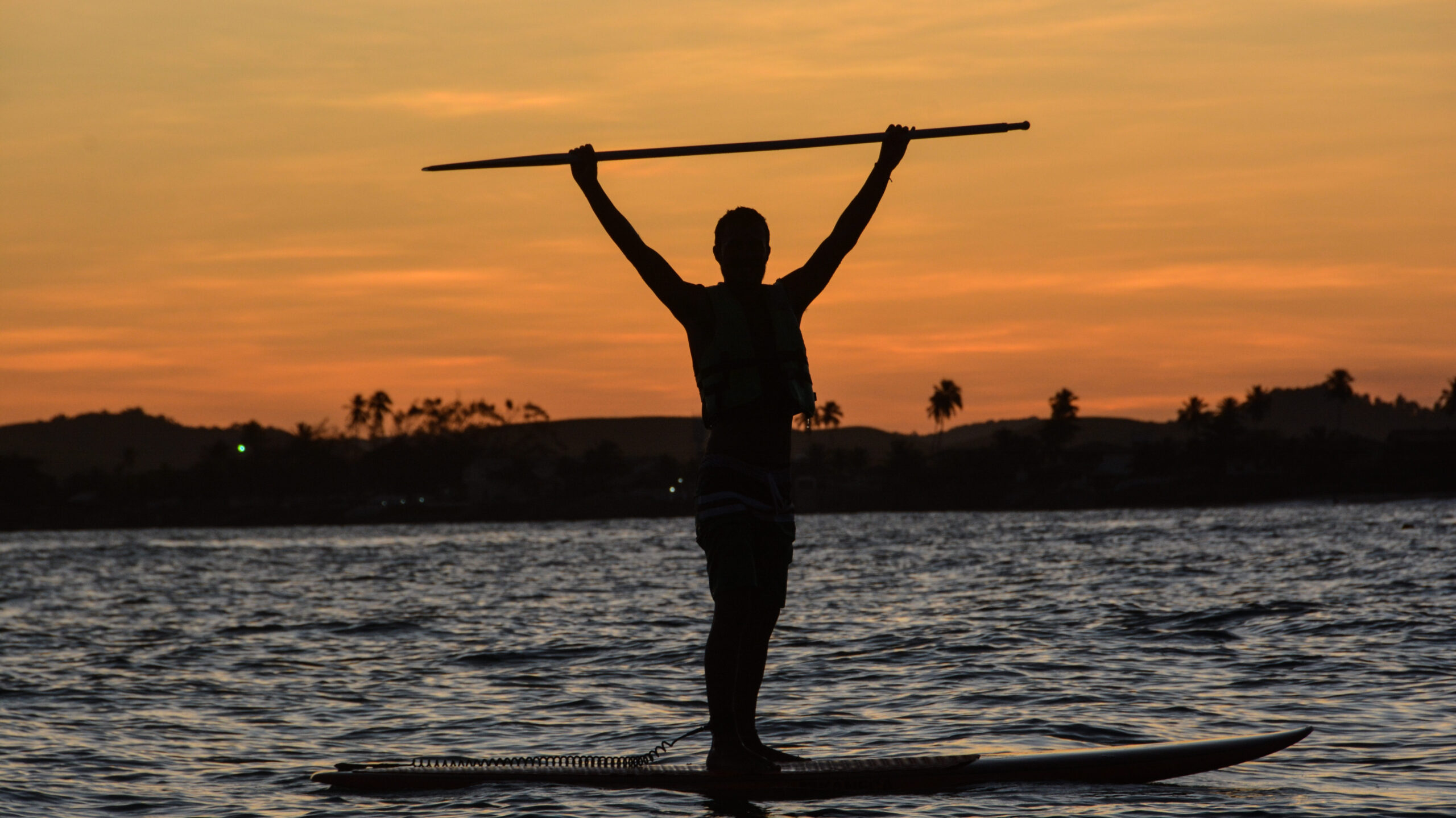 Banhista praticando stand-up paddle nas águas calmas da barreira de recifes em Muro Alto.